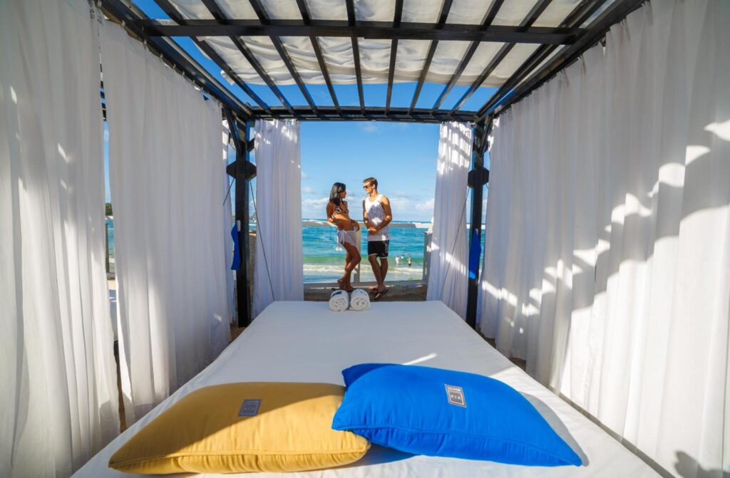 a man and woman standing on a bed with white curtains