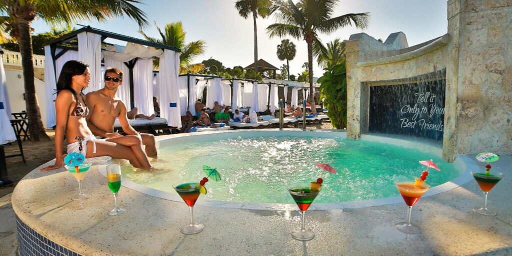 a woman sitting in a hot tub with drinks in front of her