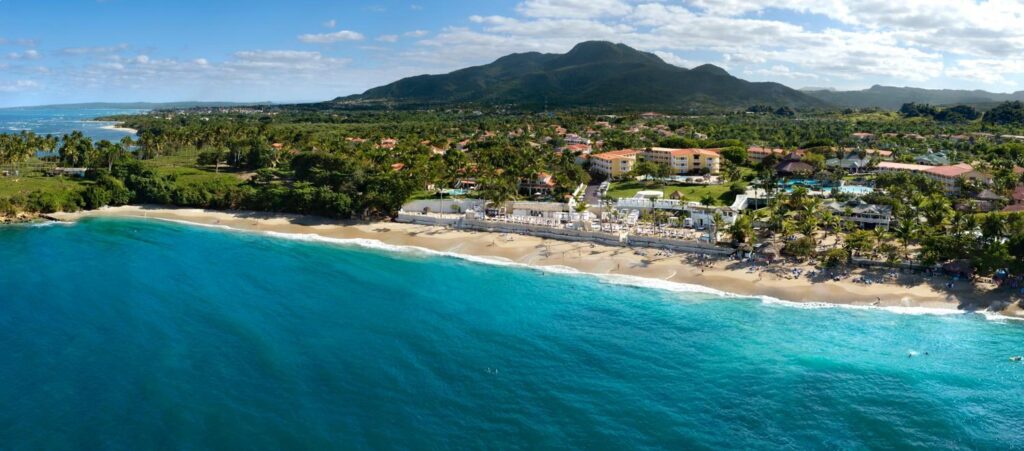 a beach with buildings and trees and a body of water
